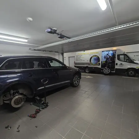 Zamjena kotača na osobnom vozilu u garaži, uz servisno vozilo