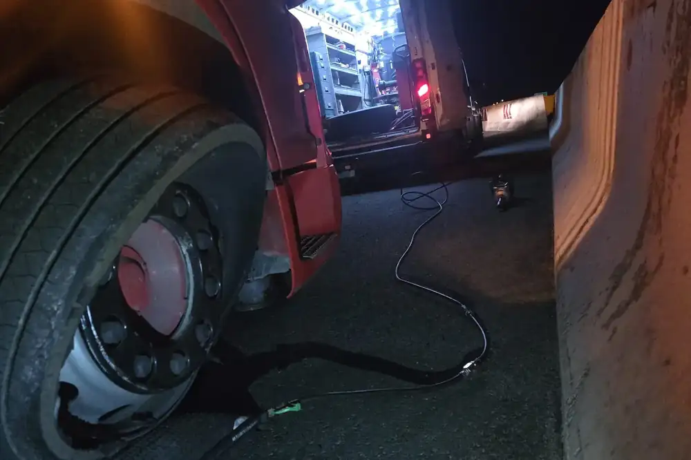Rad na kotaču teretnog vozila noću, uz rasvjetu iz servisnog vozila