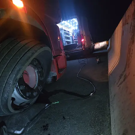 Rad na kotaču teretnog vozila noću, uz rasvjetu iz servisnog vozila