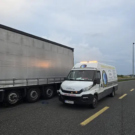 Servisno vozilo s rotacijskim svjetlima uz poluprikolicu na autocesti